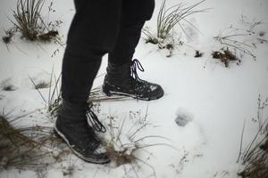 schwarz Stiefel im Winter. Mädchen im Herren Schuhe. Schnee Schuhe schwarz Kleidung. foto