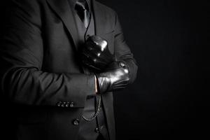 Mafia Gangster im dunkel passen ziehen auf schwarz Leder Handschuhe. Drohung von Achtung und physisch Gewalt. foto