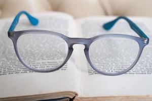 hellblaue Lesebrille isoliert auf einem Buch foto