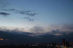 Sonnenuntergang dunkel Blau Wolke mit Weiß golden Licht Himmel Hintergrund und Stadt Licht Mitternacht Abend Zeit foto