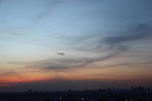 Sonnenuntergang dunkel Blau Wolke mit Weiß golden Licht Himmel Hintergrund und Stadt Licht Mitternacht Abend Zeit foto