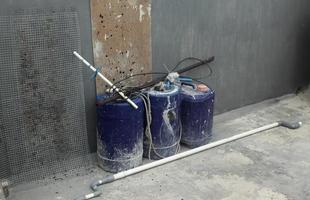 Blau Plastik Farbe Wasser Eimer auf Beton Fußboden und grau Wände und Holz Planke neben Stahl Gitter Gittergewebe neben Es. foto