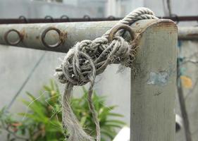 lose unsicher Weiß alt Seil Faden gebunden oben auf Stahl Zaun. foto
