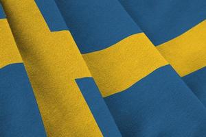 schwedenfahne mit großen falten, die im innenbereich unter dem studiolicht wehen. die offiziellen symbole und farben im banner foto