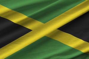 Jamaika-Flagge mit großen Falten, die unter dem Studiolicht im Innenbereich winken. die offiziellen symbole und farben im banner foto
