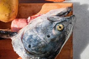 lohikeitto Fisch Suppe Vorbereitung, traditionell finnisch und karelisch Suppe, Lachs Kopf, und Gemüse gelegt aus auf das Tisch, oben Aussicht Nahansicht foto