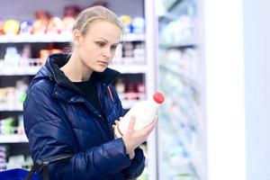 Frau in einem Lebensmittelgeschäft, das Milch hält foto