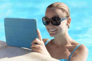 Frau in einem Pool mit einer Tablette foto