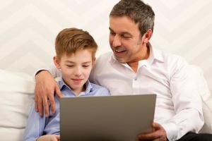 Junge und Vater benutzen zusammen einen Laptop foto
