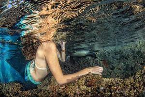 Meerjungfrau, die unter Wasser im tiefblauen Meer schwimmt foto