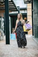 Porträt einer jungen glücklichen Frau mit Einkaufstüten, die auf der Straße gehen foto