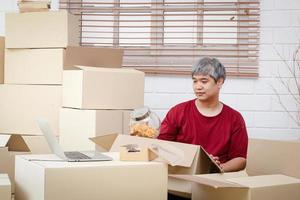 Fett Mann mit Weiß Haar ist Verpackung Produkte in Papier Kisten zum Lieferung das Konzept von klein Unternehmer, online Handel Geschäft, liefern Waren durch Mail foto