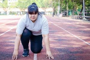 Fett asiatisch Frau vorbereiten zum Joggen im das Morgen Laufen Feld. Konzept von Gewicht Verlust, Übung zum das Wohlbefinden von fettleibig Personen. das Konzept von Wettbewerb Muss leisten das beabsichtigt Ziele. foto