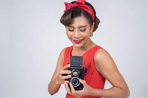 glücklicher modischer Frauenfotograf, der eine Retro-Weinlesekamera hält foto