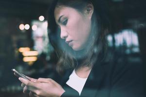 junge Frau, die Nachrichten auf Handy während der Ruhe im Café liest