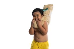 kleiner asiatischer Junge, der einen großen Teddybär lokalisiert auf weißem Hintergrund hält foto