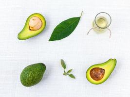 Avocados und Öl auf weißem Hintergrund foto