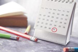 Fristkonzept mit roter Markierung am Kalendertag mit Buch und Stiften auf dem Tisch foto