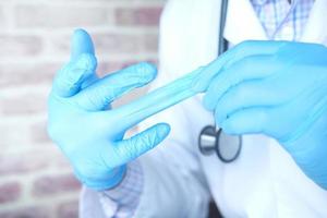 männlicher Arzt zieht medizinische Handschuhe aus, Nahaufnahme foto