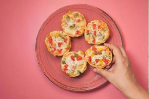 Draufsicht der Hand des Mannes, die ein Stück Pizza von einem Teller pflückt foto