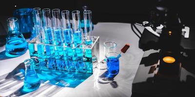 Fläschchen und Flaschen mit blauer Flüssigkeit neben wissenschaftlichen Geräten foto