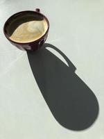 Kaffee Latte mit langem Schatten auf einem weißen Tisch
