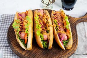 heiß Hund mit Kopfsalat, Tomaten und eingelegt Zwiebeln. gegrillt Brötchen mit Würstchen foto