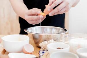 Mann im das Küche Kochen ein Teig. Hände geht kaputt ein Ei in ein Schüssel ,Hände Gießen gebissen Ei ,Backen Konzept foto