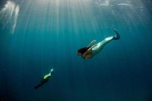 Meerjungfrau, die mit einem Siegel im tiefblauen Meer unter Wasser schwimmt foto