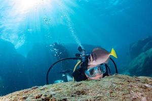 schönes Latina-Tauchermädchen beim Berühren eines Fisches foto