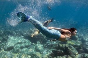 Meerjungfrau, die mit einem Siegel im tiefblauen Meer unter Wasser schwimmt foto