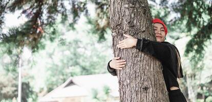 zufrieden jung Frau umarmen ein groß Baum mit ein glückselig Ausdruck mit Kopieren Raum foto