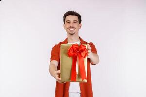 Porträt eines glücklichen jungen kaukasischen Mannes, der einen Geschenkkarton zeigt und die Kamera einzeln auf weißem Hintergrund betrachtet foto