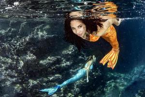 Meerjungfrau, die unter Wasser im tiefblauen Meer schwimmt foto