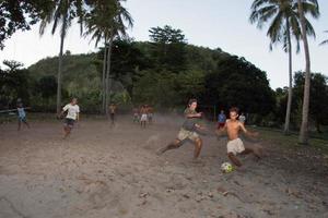 gili asahan, indonesien - august 22 2016 - jungen spielen fußball bei sonnenuntergang auf einem palmenfeld in der nähe des strandes foto