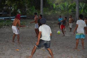 gili asahan, indonesien - august 22 2016 - jungen spielen fußball bei sonnenuntergang auf einem palmenfeld in der nähe des strandes foto