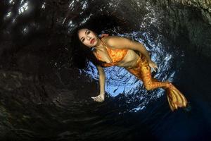 Meerjungfrau, die unter Wasser im tiefblauen Meer schwimmt foto