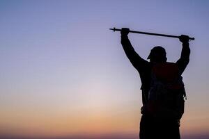 Silhouette von Jubel Wandern Mann öffnen Waffen zu das Sonnenaufgang Stand auf Berg foto