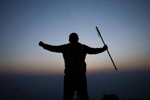 Silhouette von Jubel Wandern Mann öffnen Waffen zu das Sonnenaufgang Stand auf Berg foto