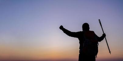 Silhouette von Jubel Wandern Mann öffnen Waffen zu das Sonnenaufgang Stand auf Berg foto