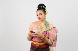 jung schön Frau Kleid oben im thailändisch Nord Region Pose mit Smartphone foto