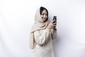 ein unzufrieden jung asiatisch Muslim Frau sieht aus verärgert tragen ein Hijab gereizt Gesicht Ausdrücke halten ihr Telefon foto