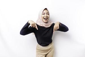 aufgeregt asiatisch Muslim Frau Hijab zeigen beim das Kopieren Raum unten ihr, isoliert durch Weiß Hintergrund foto