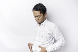 Ein Porträt eines unsicheren dicken asiatischen Mannes hält das Fett auf seinem Bauch foto