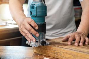 tischler verwenden router trimmer, um das material zu entfernen und den patch auf holz in der werkstatt, im diy maker und im holzbearbeitungskonzept auszuschneiden. selektiver Fokus foto