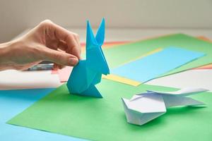 DIY-Konzept. Frau macht Origami-Osterhasen aus farbigem Papier. Origami-Unterricht foto