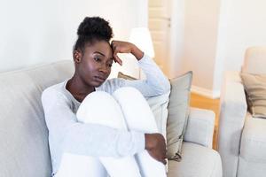 traurig nachdenklich besorgt afrikanisch amerikanisch Mädchen sitzen auf Sofa suchen Weg Gefühl deprimiert zweifelhaft, einsam betont verärgert jung schwarz Mädchen Denken von psychologisch Problem Denken Bedauern Über Fehler foto