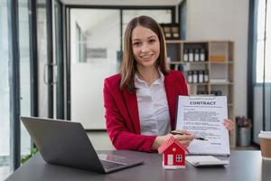 buchhalter, geschäftsmann, immobilienmakler, geschäftsmann, der den kunden ein modellhaus zusammen mit dokumenten zur rechnung der hauszinsen zur unterzeichnung durch den kunden überreicht. foto