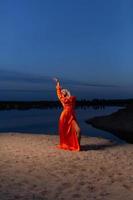 jung Frau im Orange Kleid posieren beim das Hintergrund von Blau Himmel foto