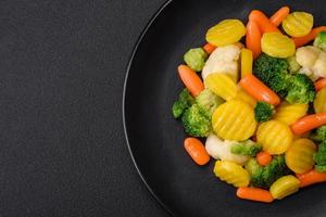 köstlich frisch Gemüse gedämpft Möhren, Brokkoli, Blumenkohl auf ein schwarz Teller foto